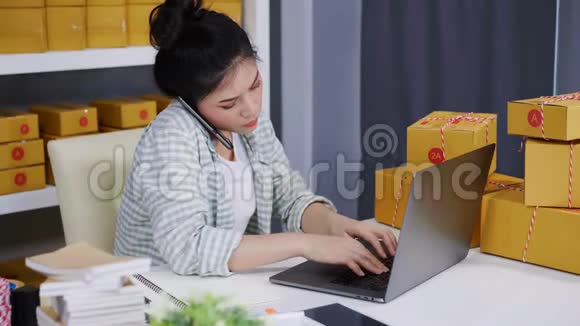 女人在智能手机上讲话用电脑手提电脑从家庭办公室在线销售产品视频的预览图