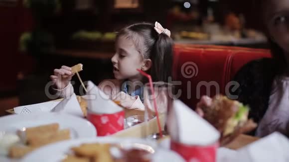 一个在快餐里吃奶酪棒的小漂亮女孩快餐店视频的预览图