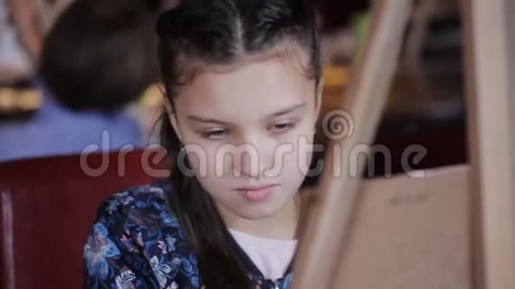 一个可爱的小女孩画在画布上在一个明亮的房间里视频的预览图