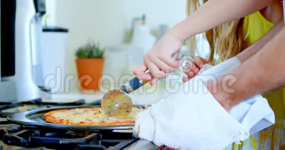 父亲和女儿切厨房里的披萨视频的预览图