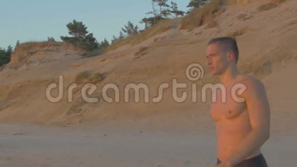 肌肉发达的白种人在海滩上行走海浪在他身后坠毁4k视频的预览图
