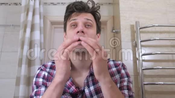 疲惫的醒着男人在浴室里宿醉使自己井井有条贴在眼睛下面视频的预览图