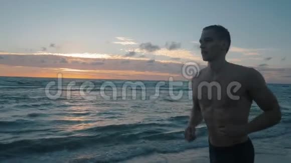 年轻的自由男运动员在日出时在平静的海面上奔跑视频的预览图