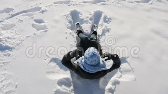 女孩戴着蓝帽子躺在雪地上视频的预览图