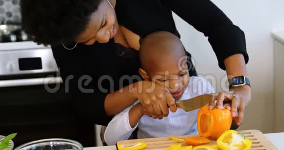母亲和儿子在家厨房里切菜视频的预览图
