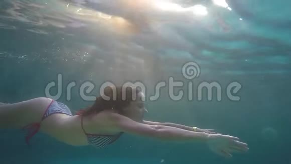 年轻漂亮的女人正在水下缓慢地通过阳光游泳1920x1080视频的预览图