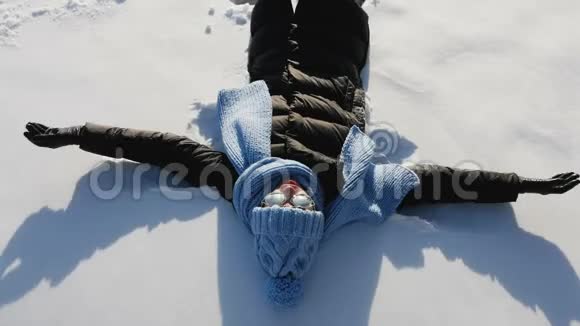 女孩戴着蓝帽子躺在雪地上视频的预览图