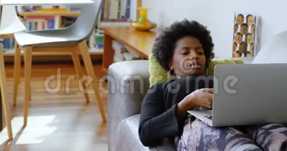 女人在家里沙发上用手提电脑和手机聊天视频的预览图