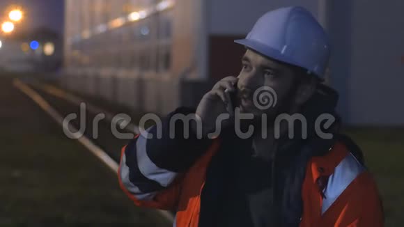 年轻快乐的工人戴着安全帽晚上通过电话交谈4k视频的预览图