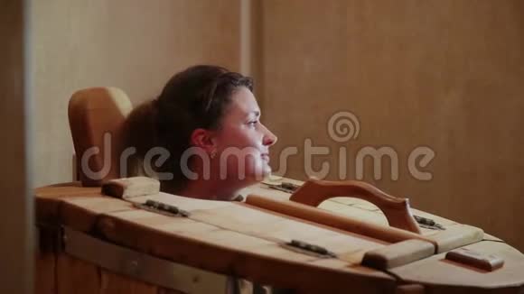 一家温泉沙龙里的雪松桶里冒出一个女人的头金发女人通过蒸汽程序恢复视频的预览图