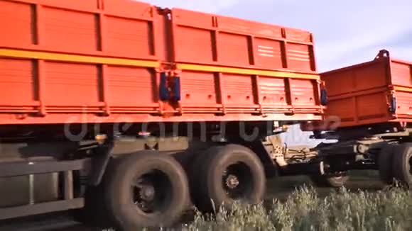 卡车沿着农田行驶在农村公路上场景在农村公路上安装带有拖车的经过橙色卡车视频的预览图
