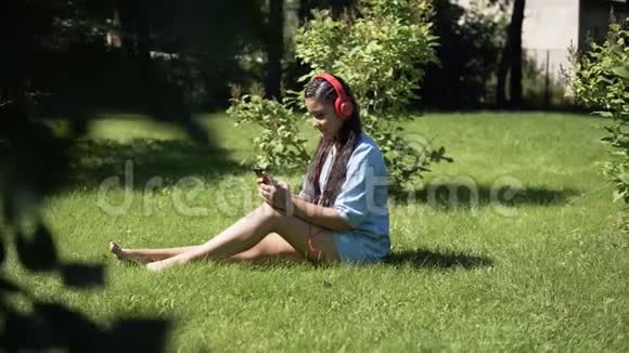 坐在公园草地上用耳机听音乐的女孩4公里视频的预览图