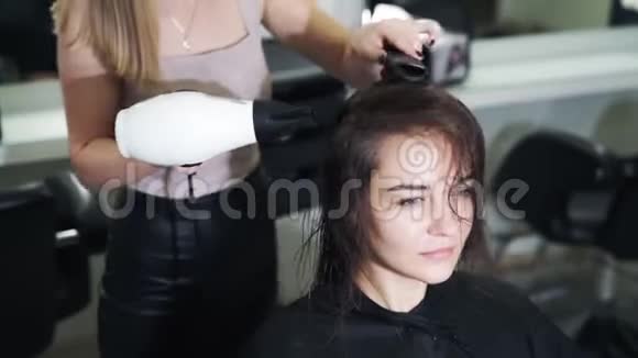 关闭理发师用吹风机擦干女性湿发慢动作视频的预览图