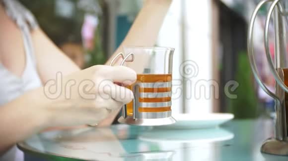 那个女孩正在喝茶坐在一家夏季咖啡馆里透明玻璃视频的预览图