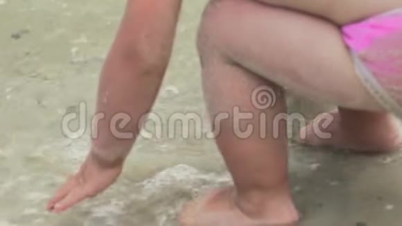 一个小孩子在海滩上的水中飞溅慢动作视频的预览图