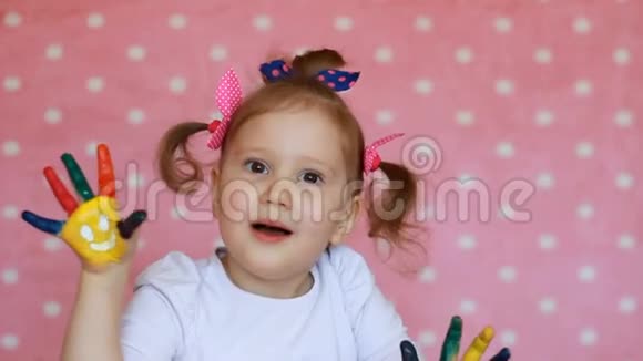 快乐的小女孩五颜六色的画手在粉红色的背景上微笑有趣的儿童艺术家有脏手掌视频的预览图