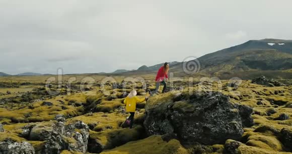 冰岛两名妇女在熔岩上行走的鸟瞰图游客在岩石上徒步旅行感受自由和快乐视频的预览图