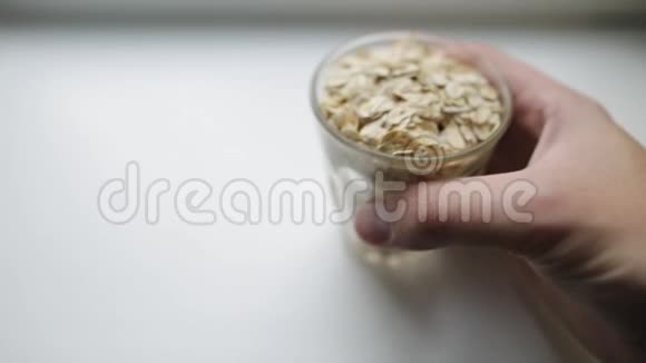 健康早餐燕麦粥一名白人男子的手把透明玻璃和大燕麦片放在白色视频的预览图