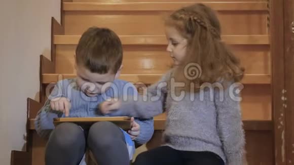 小孩子坐在楼梯上玩平板电脑视频的预览图