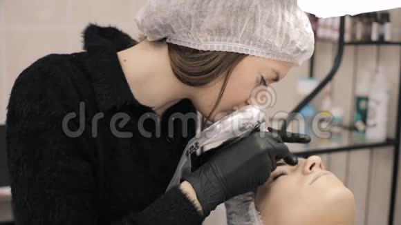 特写美容师用黑色橡胶的手在眉毛上涂上永久的化妆眉毛纹身视频的预览图