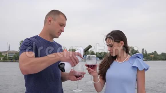 快乐的一对情侣在背景海中喝着红色的小茶浪漫的情侣们在度假手里拿着眼镜男女视频的预览图