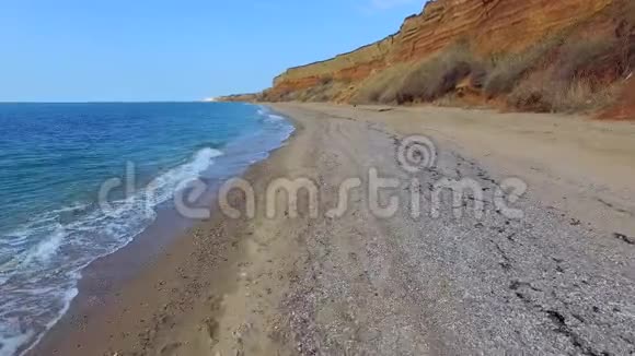 沿着棕色岩石旁边的海滩线走视频的预览图