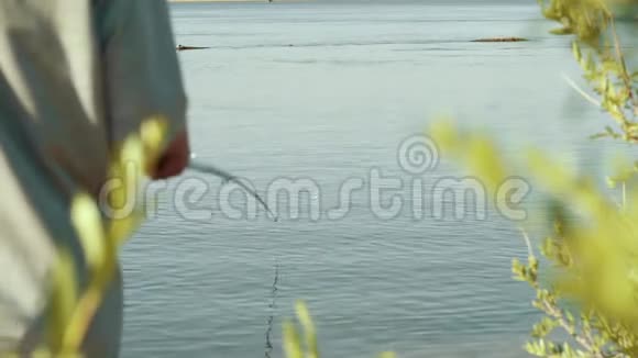 年轻的渔夫拿着钓竿手里拿着浮子等待着被咬的背影视频的预览图