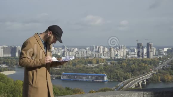 有胡子的家伙抽烟在城市背景下看文件视频的预览图