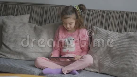 一个小女孩拿着一个便携式平板电脑在家学习一个带眼镜的孩子仔细地看着这个小玩意视频的预览图