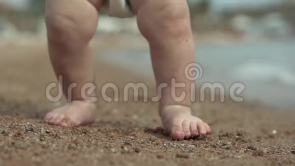 可爱的小宝宝小腿站在沙滩上的沙滩上视频的预览图