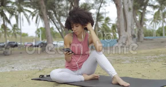 带着电话在公园垫子上的女人视频的预览图