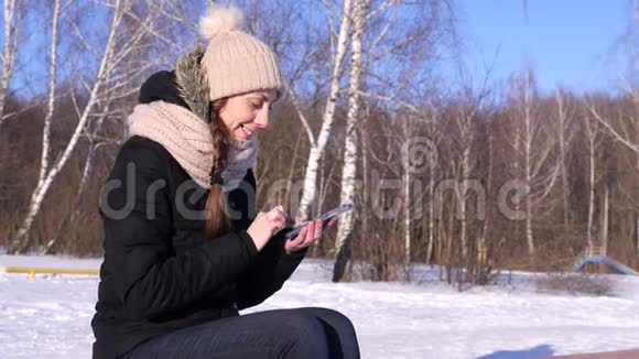 4K妇女浏览图片文字智能手机在冬季森林晴天视频的预览图