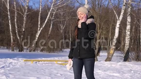 年轻女子在冬季公园打电话慢动作视频的预览图
