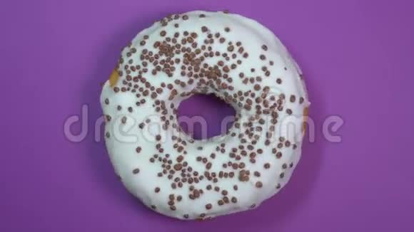 明亮和白色釉面甜甜圈与巧克力球宏观拍摄旋转在紫色背景视频的预览图