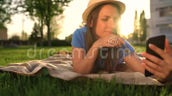 日落时躺在公园的毯子上自拍的女孩视频的预览图