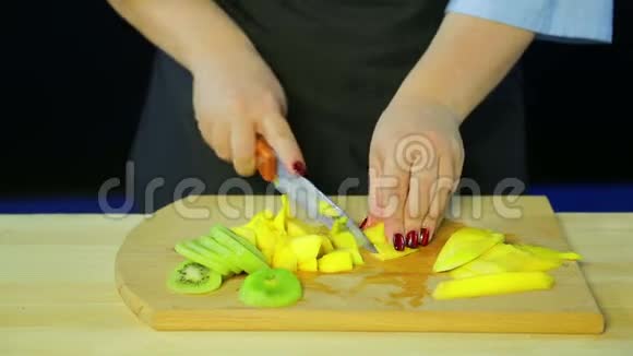 女性用手在木板上切割猕猴桃和芒果视频的预览图
