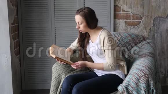 年轻漂亮的女人坐在现代椅子上看书视频的预览图