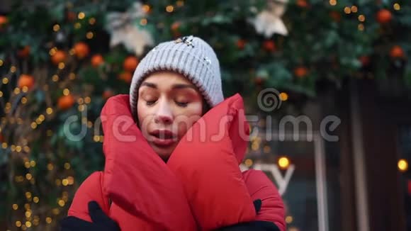 穿红色夹克的女孩试图用圣诞装饰温暖自己站在街上视频的预览图
