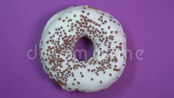 明亮和白色釉面甜甜圈与巧克力球宏观拍摄旋转在紫色背景视频的预览图