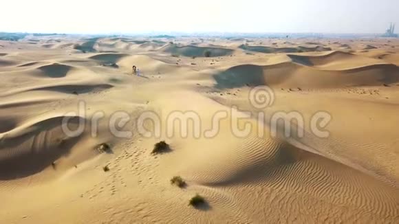 空中侦察无人机飞过沙漠贝都因人带着骆驼穿过沙漠视频的预览图