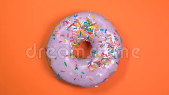 明亮而多彩的甜甜圈宏拍在橙色背景上的盘子上快速旋转视频的预览图