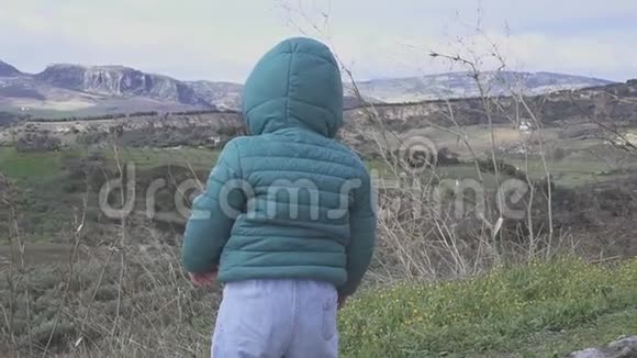 小男孩看着西班牙的山景在山上玩视频的预览图