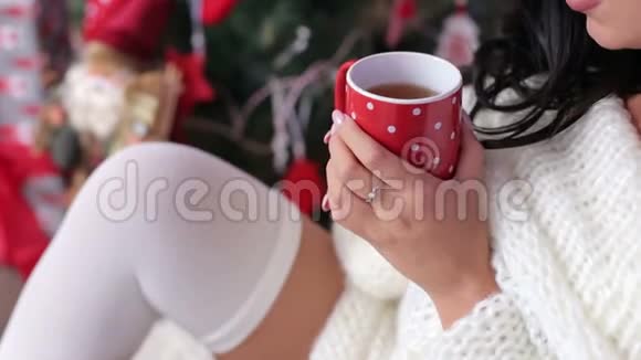 圣诞树附近妇女喝茶的特写镜头视频的预览图