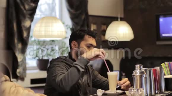 一个迪拜年轻人在咖啡馆里搅拌糖和喝咖啡视频的预览图