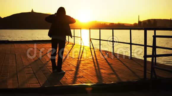 落日余晖下码头上一个女人的剪影视频的预览图