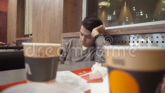 那个年轻人坐在咖啡馆里把头靠在手臂上那家伙坐着手放在头上视频的预览图