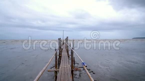 相机穿过竹桥驶向泥泞的大海视频的预览图