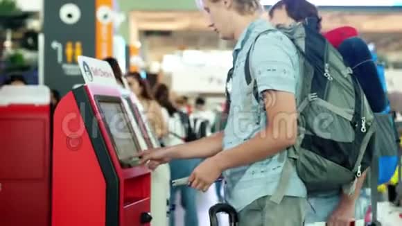 携带背包的男子在机场自助服务台办理登机手续3840x2160视频的预览图