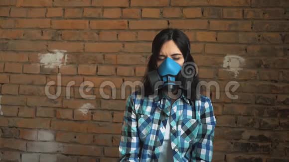 这个女孩从空气污染中摘下面具上砖墙背景呼吸面罩视频的预览图