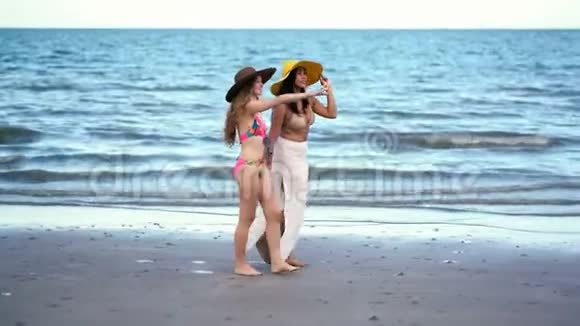穿比基尼的快乐女人在沙滩上聊天视频的预览图